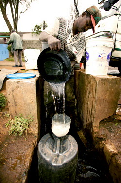 Conservation Issues: collecting water, which is in short supply Africa,conservation,conservation issue,conservation issues,water,clean water,drinking water,collect,collecting,drum,funnel,pour,pouring,urban,village,people