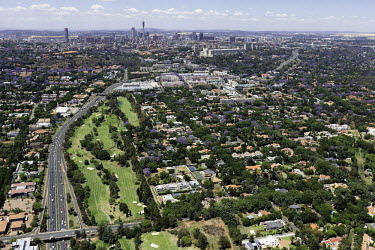 Aerial view of the main highway travelling through to the city centre in the distance - Johannesburg, South Africa Aerial,Landscape,City,Suburbs,Road,Buildings,Houses,Neighbourhood,Trees,Rooftops,Settlement,Tree-lined,Colourful,Purple,Colour,City centre,Skyline,Highway,Main road,Golf course