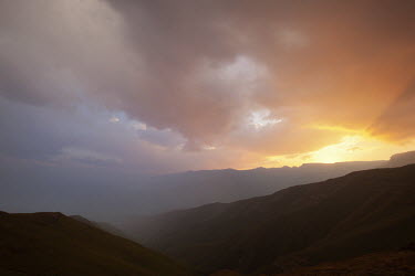 Sun set over the mountains of the Royal Natal National Park, with low clouds - South Africa colour,no people,sunset,Africa,African,Southern Africa,scenic,scenery,beauty in nature,natural world,non-urban scene,nature,outdoors,sunbeam,mountain,grassland