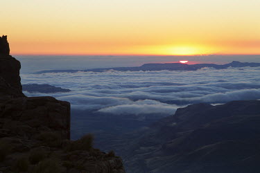 A sunset view from the Sani pass road with low clouds suspended - uKhahlamba Drakensberg Park, South Africa Sunrise,Scenic,scenery,beauty in nature,natural world,non-urban scene,nature,outdoors,Low cloud,Cloud formation,Valley,Rock formation,Landscape
