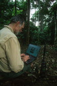 Dr Michael Loomis using laptop computer and satellite phone during elephant research Africa,conservation,conservation action,research,researcher,laptop,computer,satellite phone,elephants,African elephants,Loxodonta africana,forest,rainforest,National Park,protected area,study,Elephant