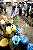 Conservation Issues: collecting water, which is in short supply Africa,conservation,conservation issue,conservation issues,water,clean water,drinking water,collect,collecting,drum,drums,pour,pouring,urban,village,people,containers,adult,adults,locals,villagers,hos