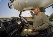 A researcher sitting in a Land Rover while tracking African wild dogs savannah,savanna,Africa,conservation,monitoring,tracks,tracking,radio tracking,warden,human,bush,African wild dog,Lycaon pictus,Carnivores,Carnivora,Mammalia,Mammals,Chordates,Chordata,Dog, Coyote, Wo