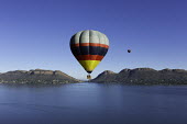 Hot air balloons rise up above a lake - South Africa Hot-air balloons,Lake,Flying,Ride,Calm,Blue sky,Clear sky,Mountains,Entertainment,Activity,Excursion,View,Colourful