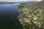 View down the river with mountains in the background - South Africa Aerial,View,Up-river,Riverside,Town,Mountains,Settlement,Slope,River,Boats,Trees,Landscape
