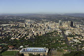 Aerial view of Johannesburg with the stadium in the foreground - Johannesburg, South Africa Aerial,Skyline,Landscape,City,City centre,Road,Clear sky,Blue sky,Highrise,Buildings,Sun,Stadium